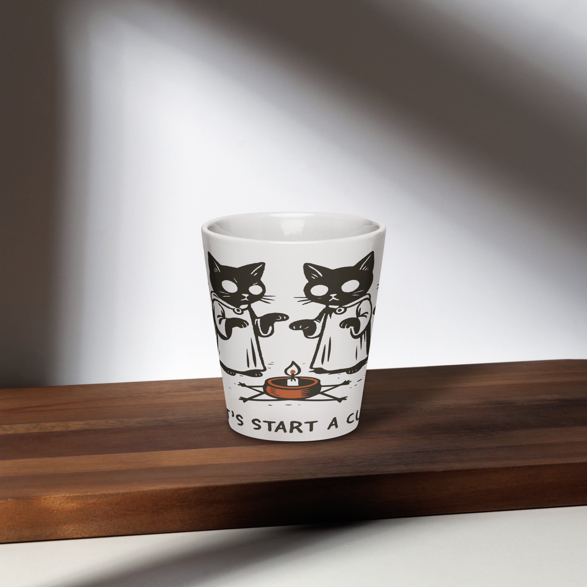 Tall ceramic latte mug featuring illustrated cats in robes gathered around a candle with the text “Let’s Start a Cult.”