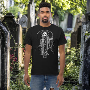 Man wearing a black Arcane Guardian t-shirt with white skeletal line art and all-seeing symbol, standing in a sunlit graveyard.