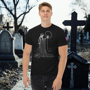 Man wearing a black Eternal Vigil t-shirt with white line art of a robed figure holding a skull, standing in a cemetery surrounded by tombstones.