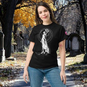 Woman wearing a black Wraith’s Reverie t-shirt with white line art of the Grim Reaper in graceful pose, surrounded by autumn trees and gravestones.