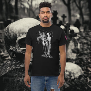 Man wearing a black Reaper’s Harvest t-shirt with white line art of a skeletal figure holding flowers, standing before a background of skulls and gravestones.