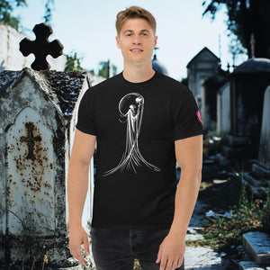 Man wearing a black Veil of Solitude t-shirt with white line art of the Grim Reaper lifting a skull, standing among sunlit mausoleums in a cemetery.