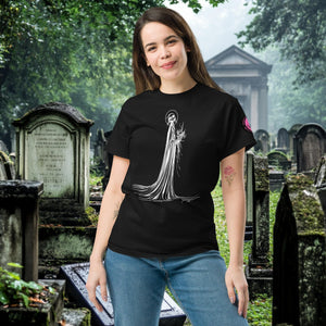 Man wearing a black Skeletal Serenity Classic Tee with white line art of Death holding flowers, standing in a gothic graveyard.