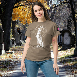 Woman wearing a brown Savana Wraith’s Reverie t-shirt with white line art of the Grim Reaper in graceful pose, surrounded by autumn trees and gravestones.
