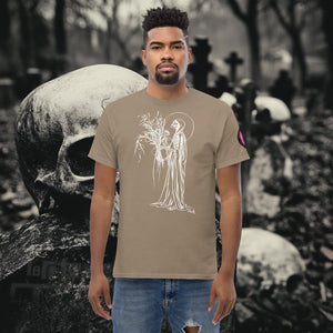 Man wearing a brown Savana Reaper’s Harvest t-shirt with white line art of a skeletal figure holding flowers, standing before a background of skulls and gravestones.