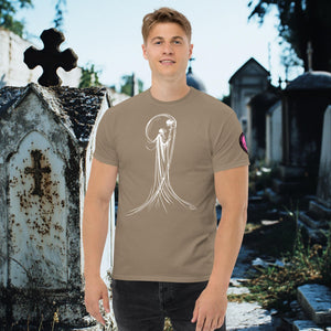 Man wearing a brown Savana Veil of Solitude t-shirt with white line art of the Grim Reaper lifting a skull, standing among sunlit mausoleums in a cemetery.