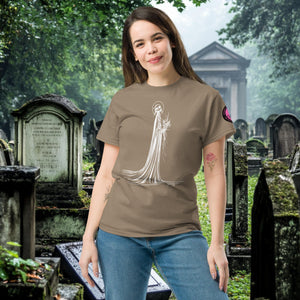 Man wearing a brown Savana Skeletal Serenity Classic Tee with white line art of Death holding flowers, standing in a gothic graveyard.