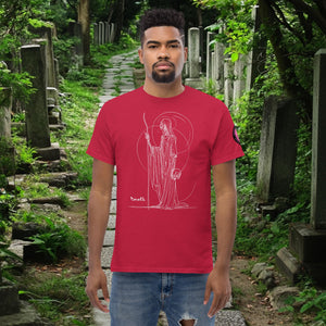 Man wearing a cardinal Grim Sentinel t-shirt with white line art of a cloaked reaper holding a scythe and skull, standing on a mossy cemetery path.