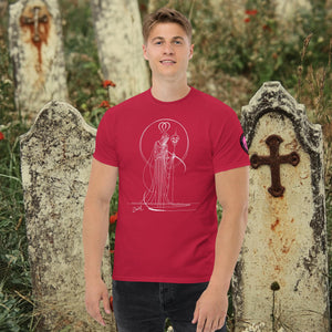 Man wearing a cardinal red Saint of Shadows t-shirt with white line art of Death holding a skull, framed by halo-like geometry, standing among aged gravestones.