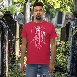 Man wearing a cardinal red Arcane Guardian t-shirt with white skeletal line art and all-seeing symbol, standing in a sunlit graveyard.