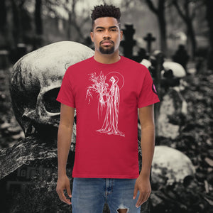 Man wearing a cardinal red Reaper’s Harvest t-shirt with white line art of a skeletal figure holding flowers, standing before a background of skulls and gravestones.