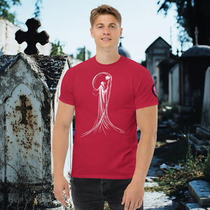 Man wearing a cardinal red Veil of Solitude t-shirt with white line art of the Grim Reaper lifting a skull, standing among sunlit mausoleums in a cemetery.