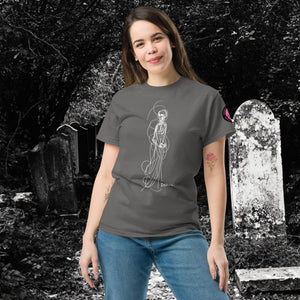 Woman wearing AETHEREUM CORPUS charcoal t-shirt with white line art corpse drawing, posed in a gothic graveyard.