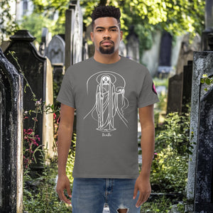 Man wearing a charcoal Arcane Guardian t-shirt with white skeletal line art and all-seeing symbol, standing in a sunlit graveyard.