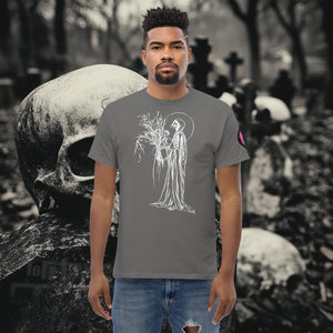 Man wearing a charcoal Reaper’s Harvest t-shirt with white line art of a skeletal figure holding flowers, standing before a background of skulls and gravestones.