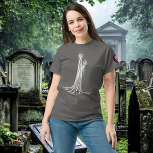 Man wearing a charcoal Skeletal Serenity Classic Tee with white line art of Death holding flowers, standing in a gothic graveyard.