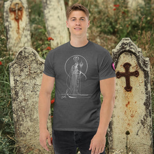 Man wearing a dark heather Saint of Shadows t-shirt with white line art of Death holding a skull, framed by halo-like geometry, standing among aged gravestones.