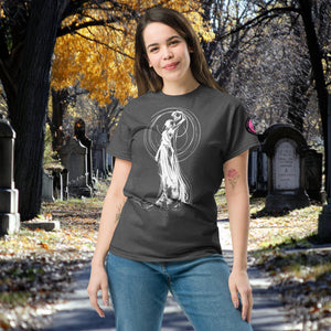 Woman wearing a dark heather Wraith’s Reverie t-shirt with white line art of the Grim Reaper in graceful pose, surrounded by autumn trees and gravestones.