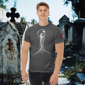 Man wearing a dark heather Veil of Solitude t-shirt with white line art of the Grim Reaper lifting a skull, standing among sunlit mausoleums in a cemetery.