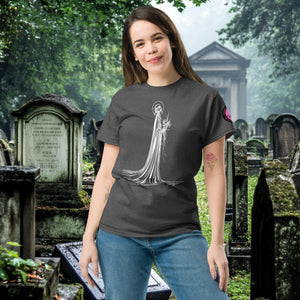 Man wearing a dark heather Skeletal Serenity Classic Tee with white line art of Death holding flowers, standing in a gothic graveyard.