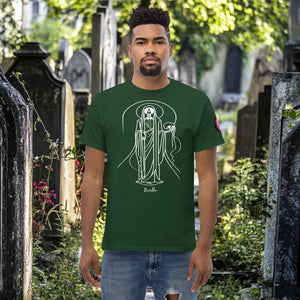 Man wearing a forest green Arcane Guardian t-shirt with white skeletal line art and all-seeing symbol, standing in a sunlit graveyard.