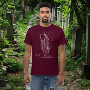 Man wearing a maroon Grim Sentinel t-shirt with white line art of a cloaked reaper holding a scythe and skull, standing on a mossy cemetery path.