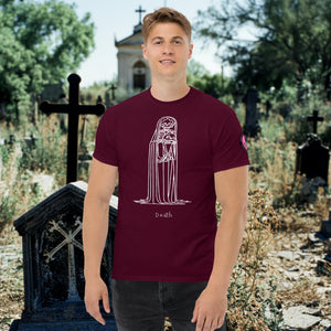 Man wearing a maroon Solitary Embrace t-shirt with white line art of a skeleton cloaked in darkness, arms wrapped around itself, standing in a graveyard.