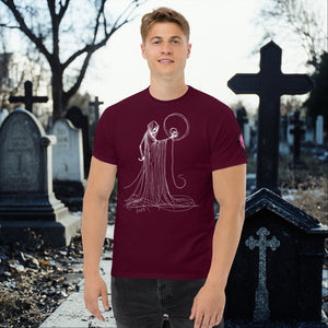 Man wearing a maroon Eternal Vigil t-shirt with white line art of a robed figure holding a skull, standing in a cemetery surrounded by tombstones.