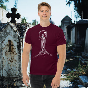 Man wearing a maroon Veil of Solitude t-shirt with white line art of the Grim Reaper lifting a skull, standing among sunlit mausoleums in a cemetery.