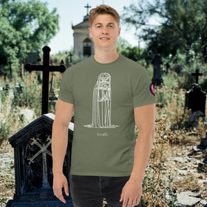 Man wearing a military green Solitary Embrace t-shirt with white line art of a skeleton cloaked in darkness, arms wrapped around itself, standing in a graveyard.