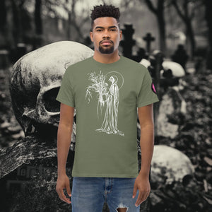 Man wearing a military green Reaper’s Harvest t-shirt with white line art of a skeletal figure holding flowers, standing before a background of skulls and gravestones.