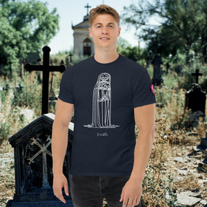 Man wearing a navy Solitary Embrace t-shirt with white line art of a skeleton cloaked in darkness, arms wrapped around itself, standing in a graveyard.