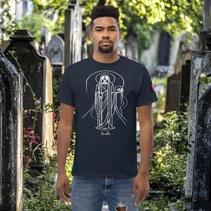 Man wearing a navy Arcane Guardian t-shirt with white skeletal line art and all-seeing symbol, standing in a sunlit graveyard.