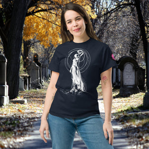 Woman wearing a navy Wraith’s Reverie t-shirt with white line art of the Grim Reaper in graceful pose, surrounded by autumn trees and gravestones.