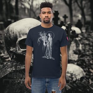 Man wearing a navy Reaper’s Harvest t-shirt with white line art of a skeletal figure holding flowers, standing before a background of skulls and gravestones.