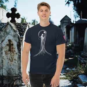Man wearing a navy Veil of Solitude t-shirt with white line art of the Grim Reaper lifting a skull, standing among sunlit mausoleums in a cemetery.
