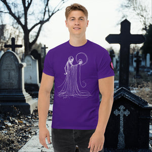 Man wearing a purple Eternal Vigil t-shirt with white line art of a robed figure holding a skull, standing in a cemetery surrounded by tombstones.