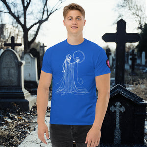 Man wearing a roayl blue Eternal Vigil t-shirt with white line art of a robed figure holding a skull, standing in a cemetery surrounded by tombstones.