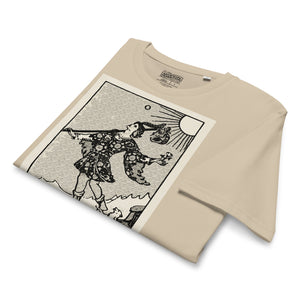 Mid-light organic cotton t-shirt featuring The Fool tarot card with cliff, dog, and sun in high-contrast woodcut rendering.
