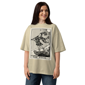 Oversized organic cotton t-shirt displaying The Fool tarot card with cliff, dog, and rising sun in modern woodcut style.