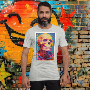 Man wearing an athletic heather Synthesized Futility Core Tee with bright multicolor skull artwork and “SYNTHESIZED” text, standing before graffiti mural.