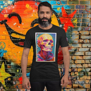 Man wearing a black heather Synthesized Futility Core Tee with bright multicolor skull artwork and “SYNTHESIZED” text, standing before graffiti mural.