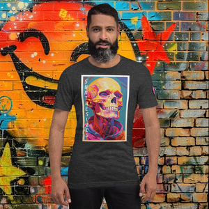 Man wearing a dark grey heather Synthesized Futility Core Tee with bright multicolor skull artwork and “SYNTHESIZED” text, standing before graffiti mural.
