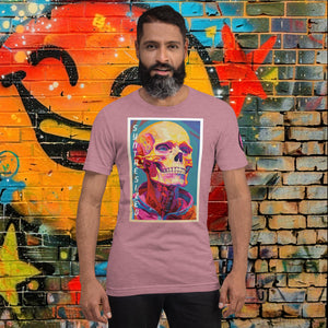 Man wearing a heather orchid Synthesized Futility Core Tee with bright multicolor skull artwork and “SYNTHESIZED” text, standing before graffiti mural.