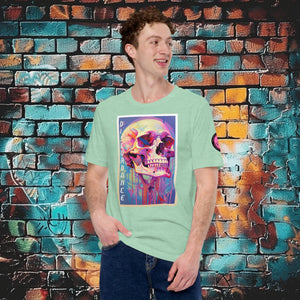 A man wearing a heather prism mint Discordance Core Tee with vibrant skull dripping in color, standing before a blue and orange graffiti wall.
