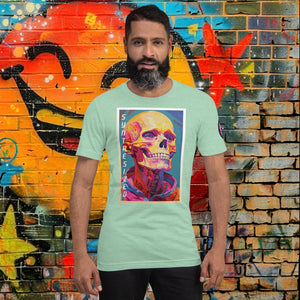 Man wearing a heather prism mint Synthesized Futility Core Tee with bright multicolor skull artwork and “SYNTHESIZED” text, standing before graffiti mural.