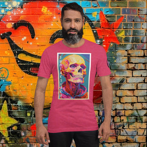 Man wearing a heather raspberry Synthesized Futility Core Tee with bright multicolor skull artwork and “SYNTHESIZED” text, standing before graffiti mural.