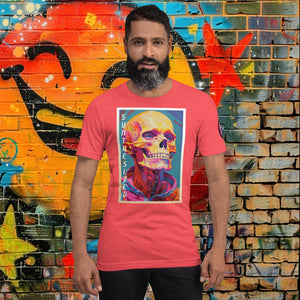 Man wearing a heather red Synthesized Futility Core Tee with bright multicolor skull artwork and “SYNTHESIZED” text, standing before graffiti mural.