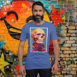 Man wearing a heather true royal Synthesized Futility Core Tee with bright multicolor skull artwork and “SYNTHESIZED” text, standing before graffiti mural.