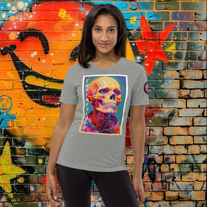 A woman wearing an athletic grey triblend Synthesized Futility Premium Tee with vibrant stylized skull, graffiti background with orange and blue tones.